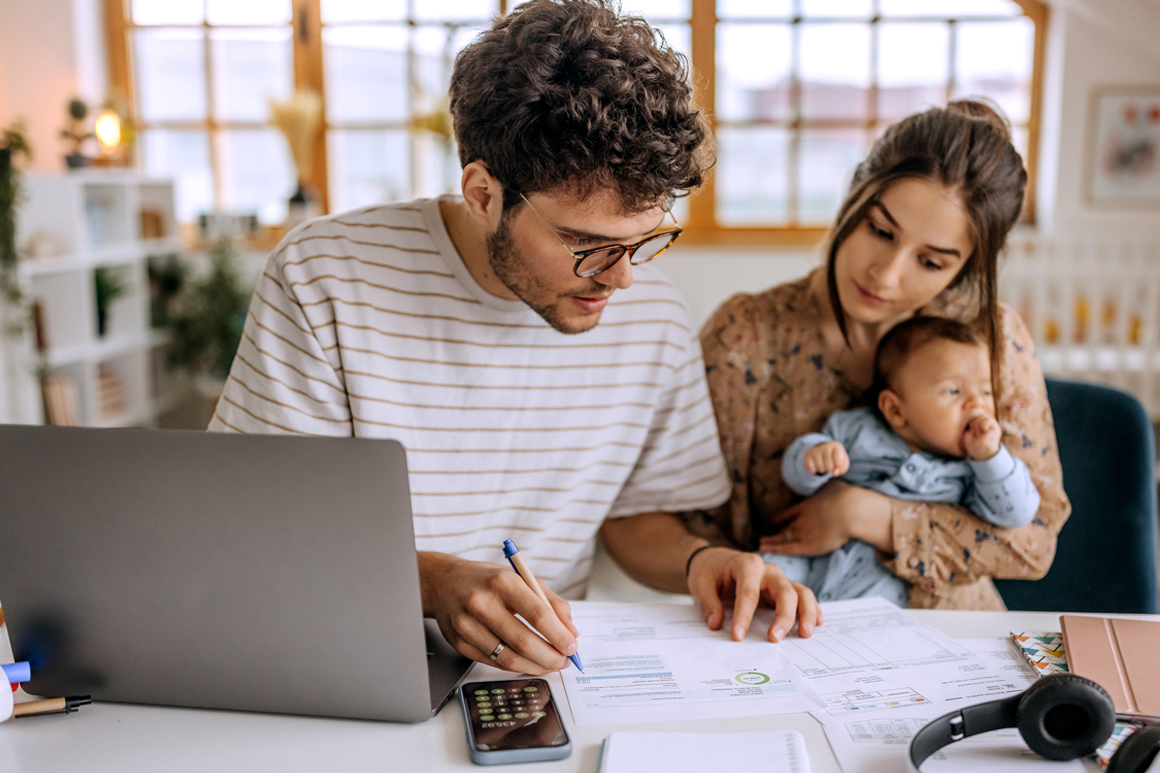 Husband and wife with their baby figuring out their financial statements and bills.